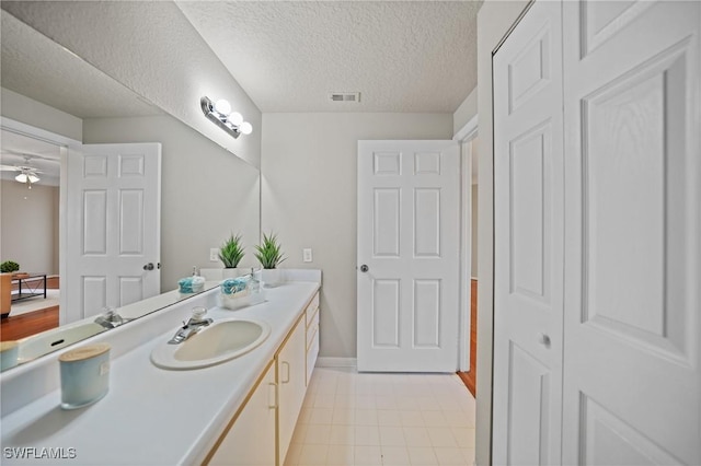 bathroom featuring vanity, ceiling fan, and a textured ceiling