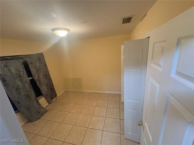 tiled empty room with a textured ceiling