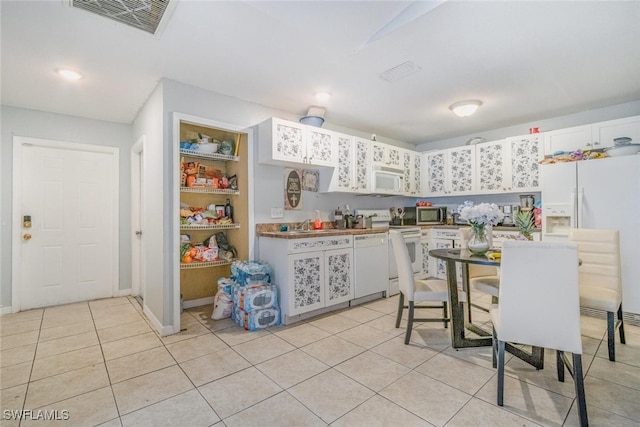 217/219 Ivan Ave S, Lehigh Acres, FL 33973 - kitchen with white cabinetry, visible vents, baseboards, white appliances, and light tile patterned flooring