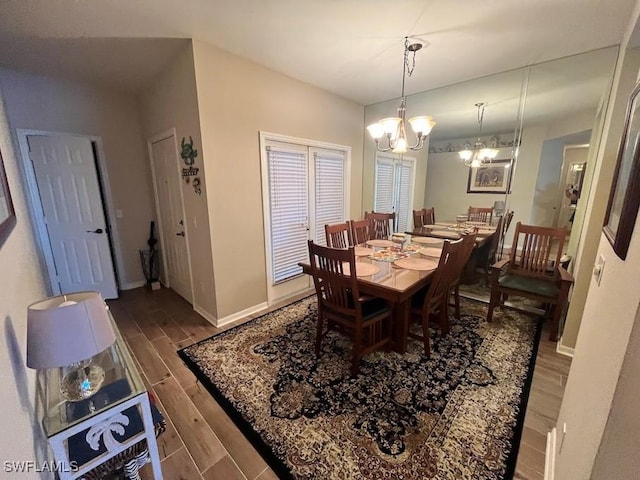 dining space featuring baseboards, wood finish floors, and an inviting chandelier