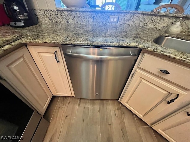 kitchen with stone countertops, white cabinets, stainless steel dishwasher, and wood finished floors