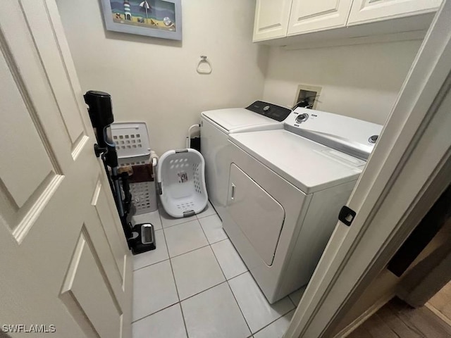 clothes washing area with cabinet space, washer and clothes dryer, and light tile patterned floors