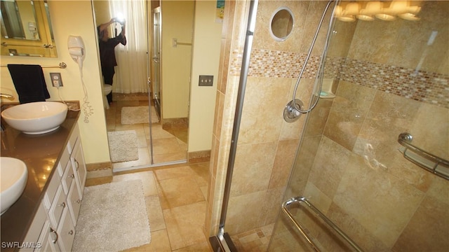 full bath featuring baseboards, double vanity, a sink, and a shower stall