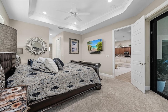 carpeted bedroom featuring ensuite bathroom, ornamental molding, ceiling fan, a raised ceiling, and a closet