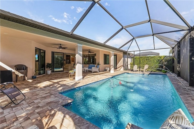 view of swimming pool featuring pool water feature, glass enclosure, ceiling fan, an outdoor hangout area, and a patio