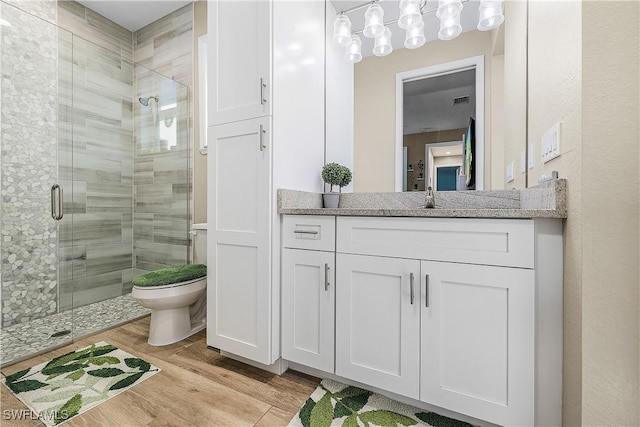 bathroom featuring hardwood / wood-style flooring, vanity, toilet, and a shower with shower door