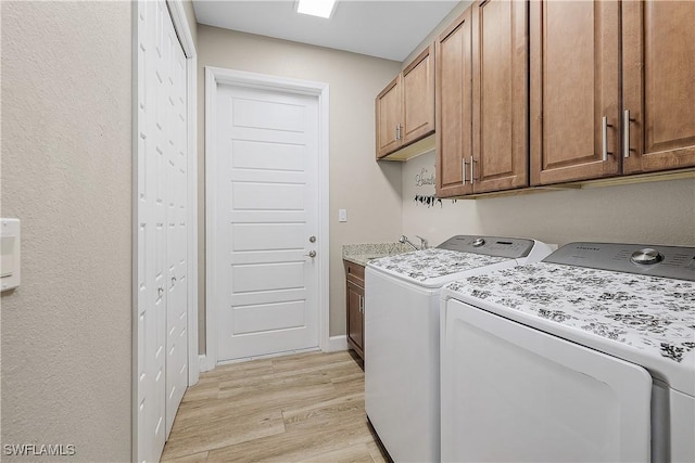 laundry area featuring cabinets, sink, washing machine and dryer, and light wood-type flooring