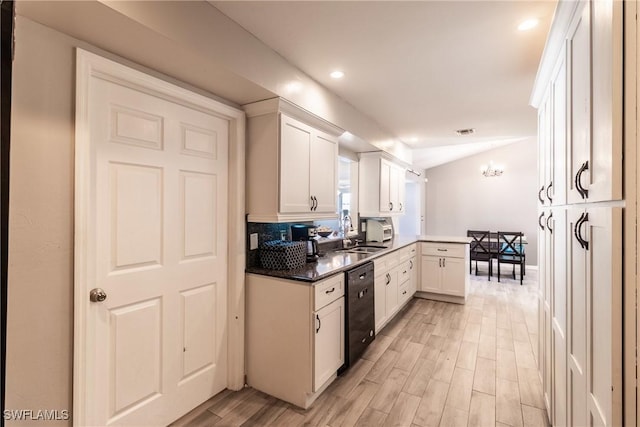 kitchen featuring sink, white cabinetry, vaulted ceiling, dishwasher, and kitchen peninsula