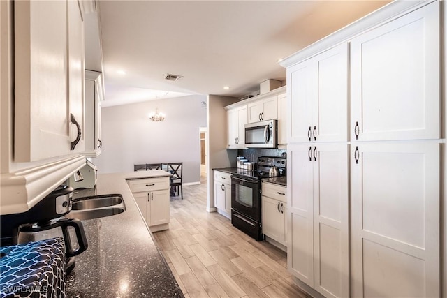 kitchen with light hardwood / wood-style flooring, dark stone countertops, an inviting chandelier, white cabinets, and black range with electric cooktop