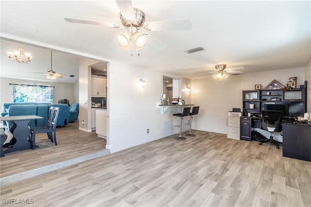 home office with ceiling fan with notable chandelier and light hardwood / wood-style floors