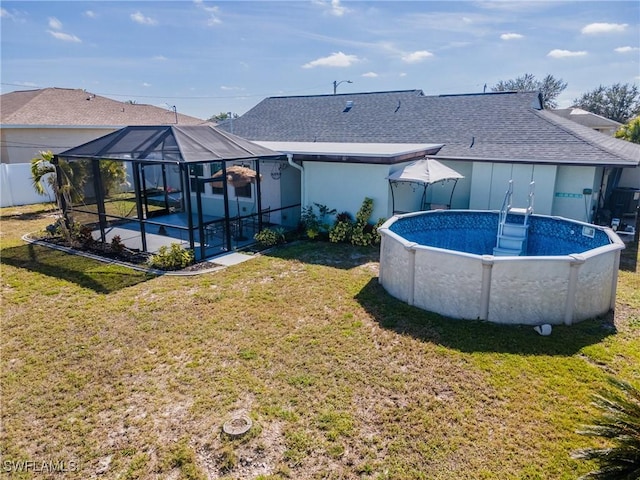 view of swimming pool featuring glass enclosure and a lawn