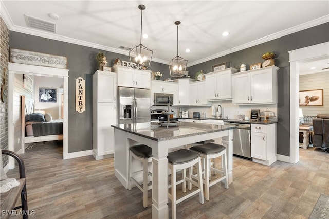 kitchen featuring white cabinetry, stainless steel appliances, a kitchen breakfast bar, a kitchen island, and decorative light fixtures