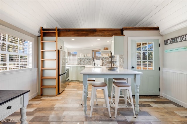 kitchen featuring stainless steel refrigerator, a kitchen breakfast bar, kitchen peninsula, and white cabinets