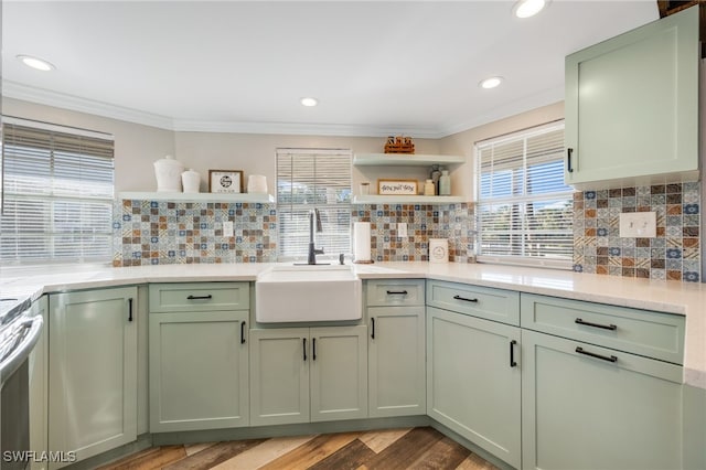 kitchen with crown molding, green cabinets, sink, and light wood-type flooring