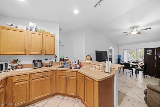 kitchen featuring sink, ceiling fan, light tile patterned flooring, vaulted ceiling, and kitchen peninsula