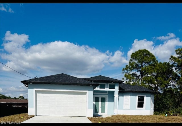 prairie-style house featuring an attached garage, concrete driveway, french doors, and stucco siding