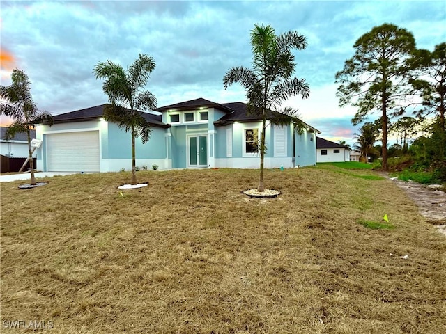 view of front of home with an attached garage, a front lawn, and stucco siding