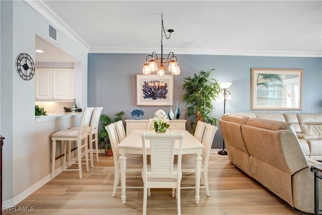 dining area with crown molding, an inviting chandelier, and light hardwood / wood-style flooring