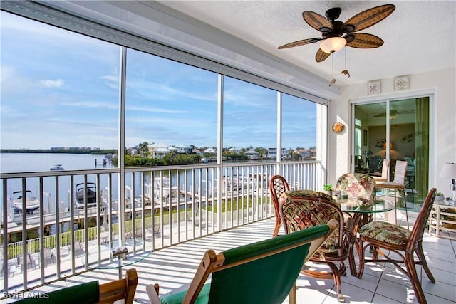 sunroom featuring ceiling fan and a water view