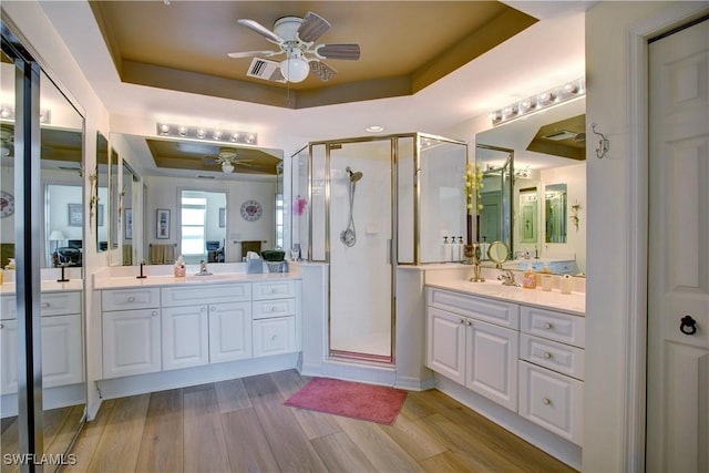 bathroom featuring a shower with door, wood-type flooring, ceiling fan, and a tray ceiling