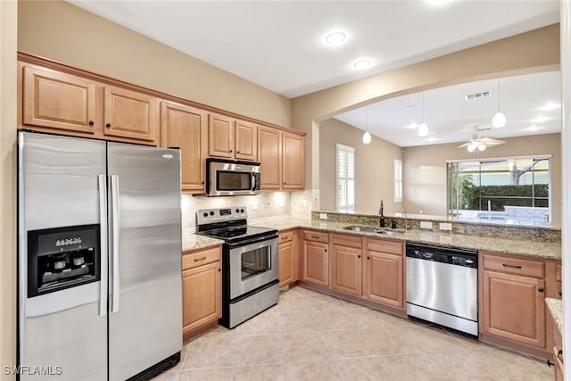 kitchen featuring light stone counters, sink, backsplash, and appliances with stainless steel finishes