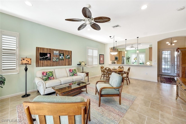 living room with light tile patterned floors and ceiling fan with notable chandelier