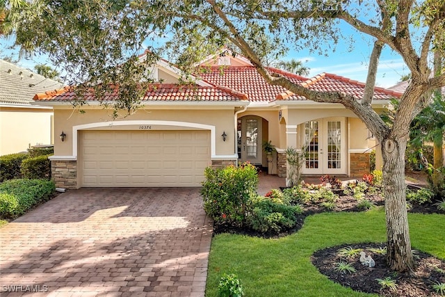 mediterranean / spanish home with a garage, a front yard, and french doors