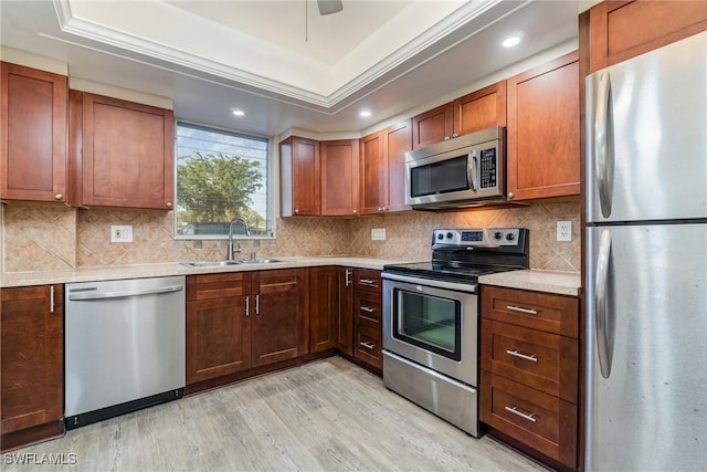 kitchen featuring appliances with stainless steel finishes, sink, backsplash, light hardwood / wood-style floors, and a raised ceiling