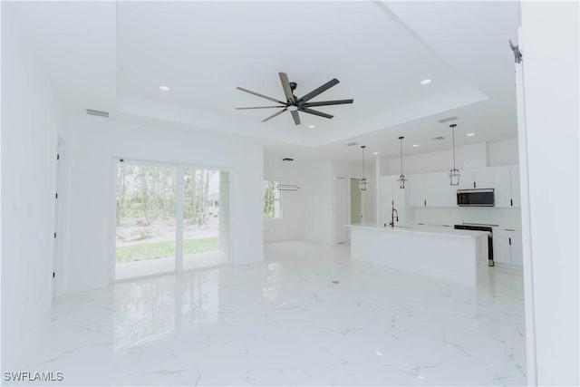 unfurnished living room with a raised ceiling and ceiling fan