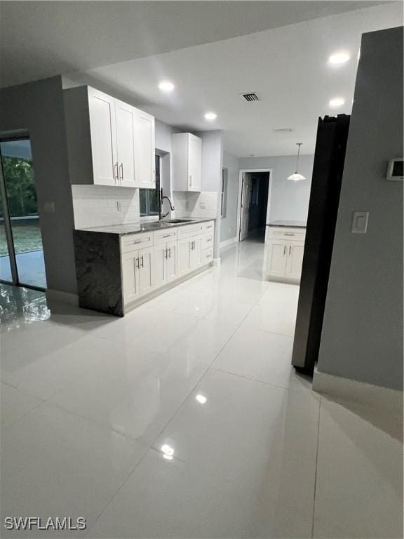 kitchen featuring hanging light fixtures, decorative backsplash, sink, and white cabinets