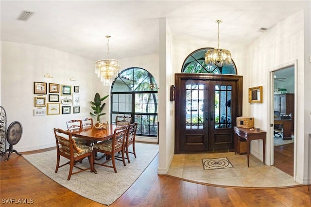 entrance foyer with french doors, a chandelier, and light hardwood / wood-style flooring