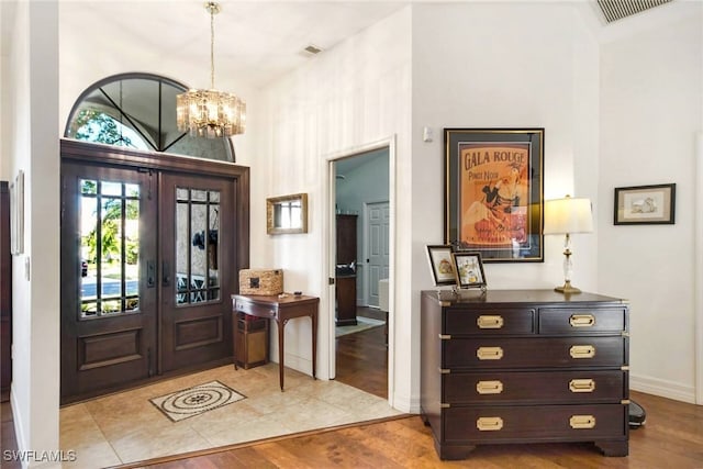 foyer with french doors, light hardwood / wood-style flooring, and a notable chandelier