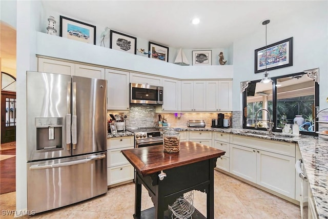 kitchen with pendant lighting, sink, light stone countertops, and appliances with stainless steel finishes