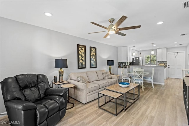 living room with ceiling fan and light hardwood / wood-style flooring