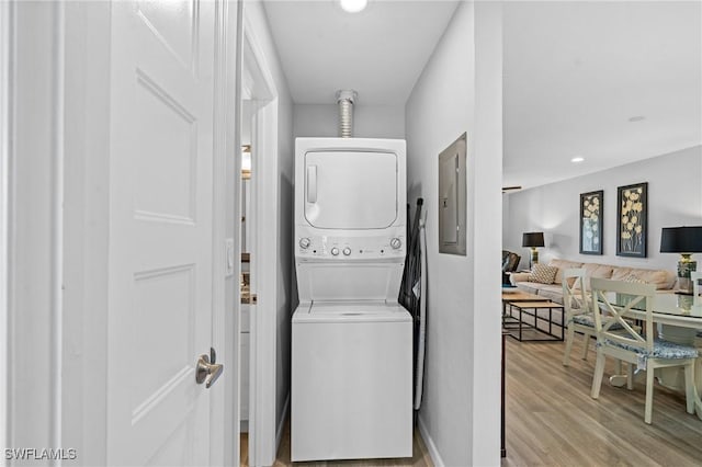 clothes washing area with light hardwood / wood-style floors, electric panel, and stacked washer / dryer