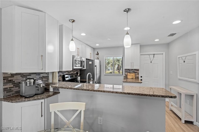 kitchen with kitchen peninsula, hanging light fixtures, and white cabinets