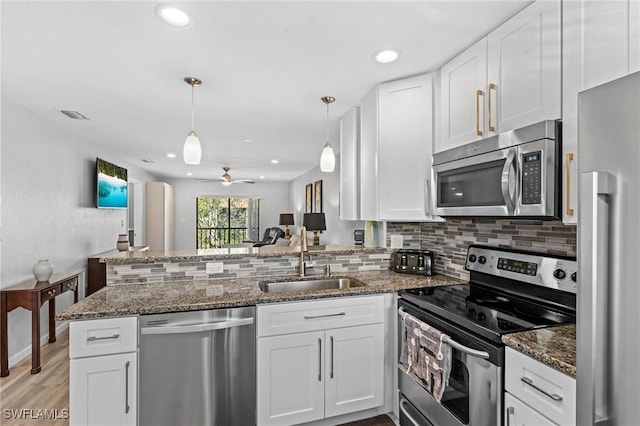 kitchen featuring stainless steel appliances, kitchen peninsula, sink, and white cabinets