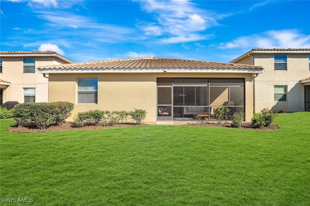 rear view of house with a lawn and a sunroom