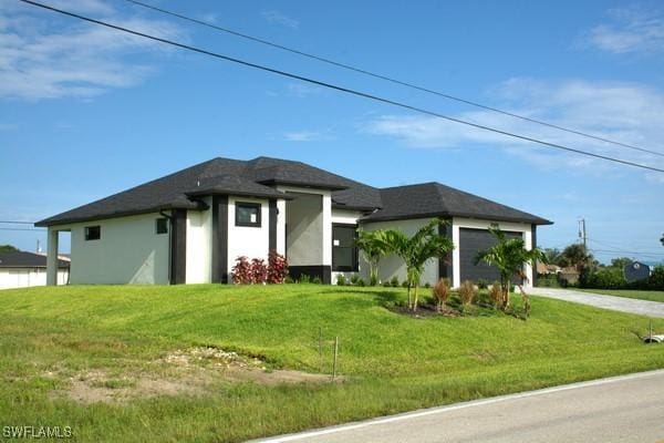 prairie-style home featuring a garage and a front lawn