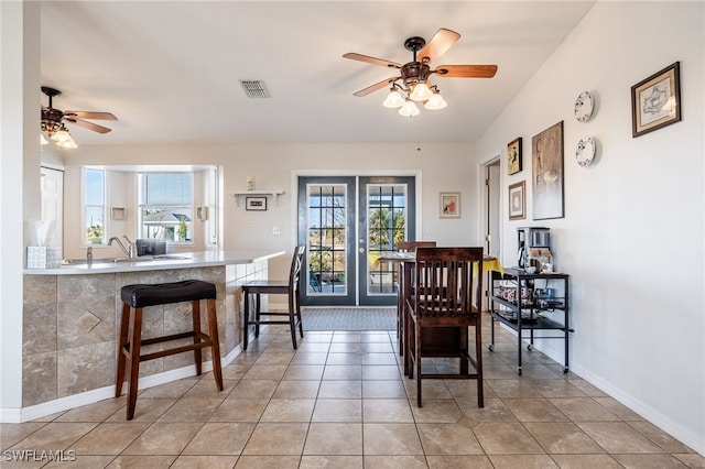 dining area featuring french doors, ceiling fan, sink, and light tile patterned floors