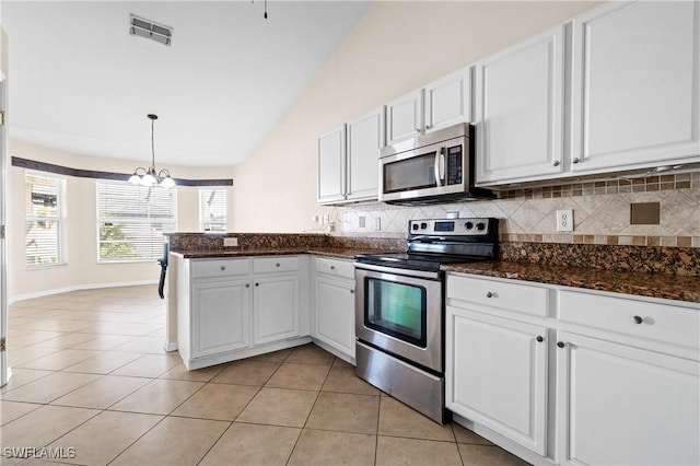 kitchen featuring decorative light fixtures, white cabinets, backsplash, light tile patterned floors, and stainless steel appliances