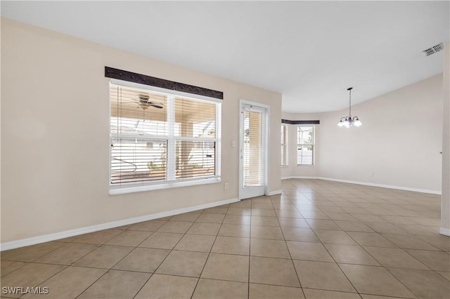 tiled spare room featuring an inviting chandelier