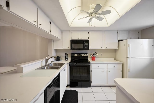 kitchen with sink, light tile patterned floors, a tray ceiling, black appliances, and white cabinets