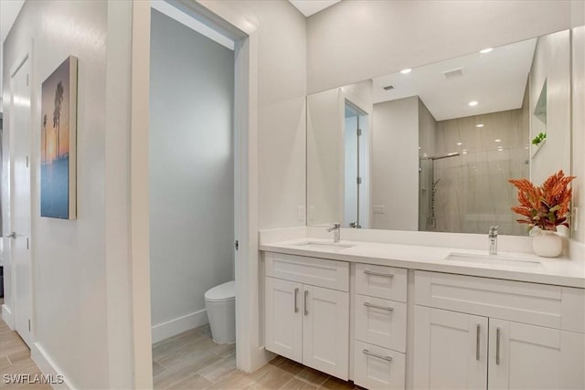 bathroom featuring vanity, a shower with shower door, and toilet