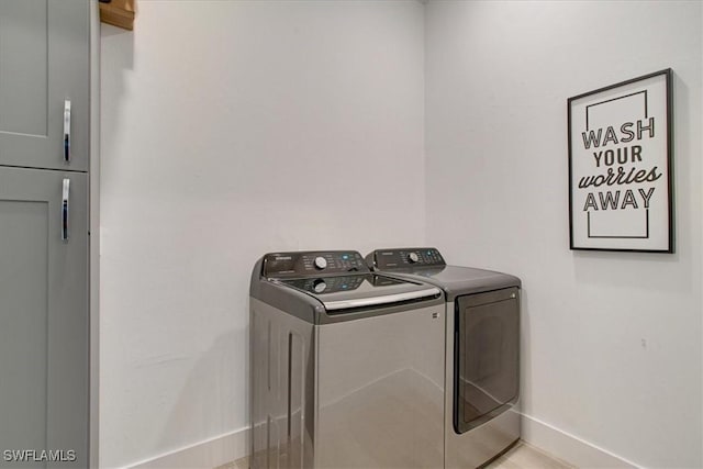 clothes washing area featuring cabinets and washer and dryer