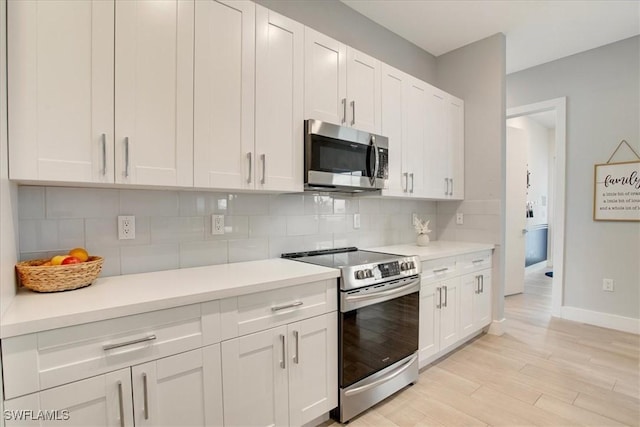 kitchen featuring white cabinetry, appliances with stainless steel finishes, decorative backsplash, and light wood-type flooring