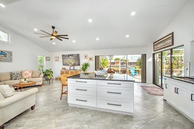 interior space with dark stone countertops, white cabinetry, a wealth of natural light, and a center island