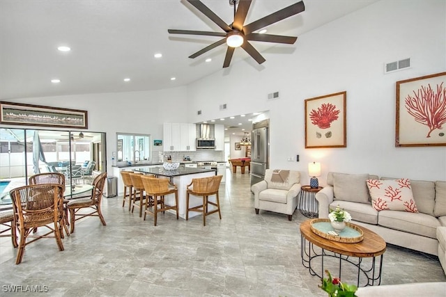 living room featuring ceiling fan, high vaulted ceiling, and sink