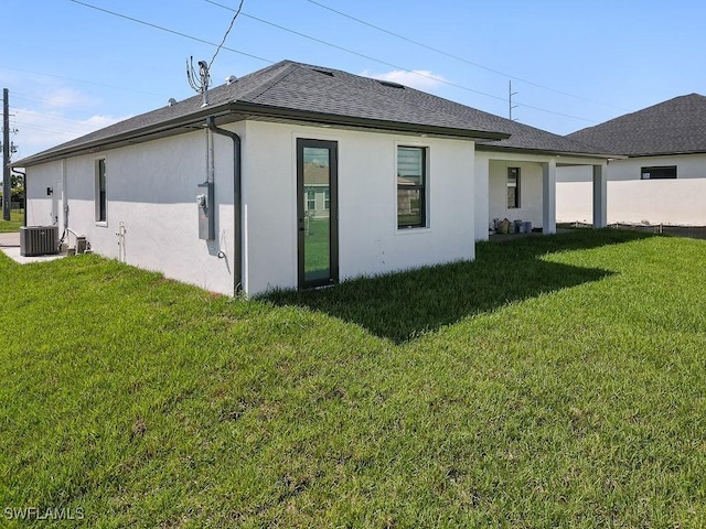 rear view of house featuring a yard and central air condition unit