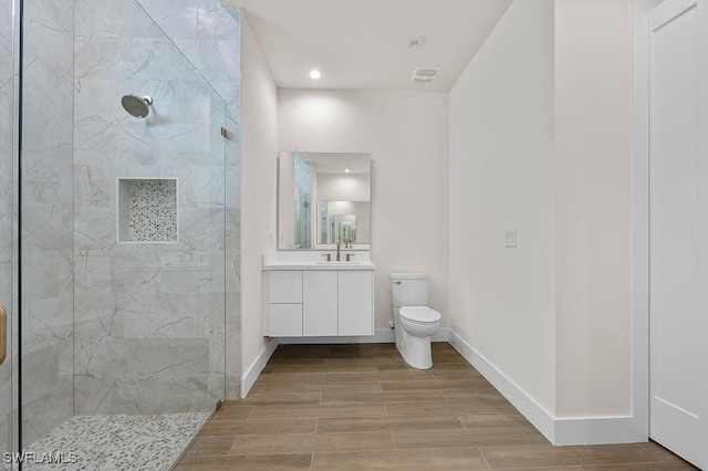 bathroom featuring vanity, toilet, and a tile shower